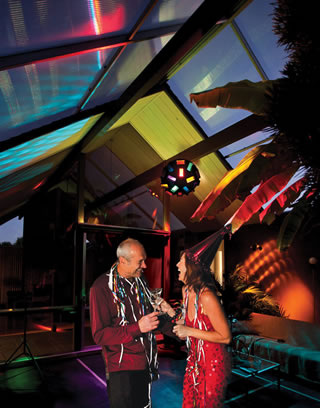 With colors swirling, Conny (left) and Andrea Marx sip their drinks to the disco ball and music under the retractable roof of their Eichler atrium. 