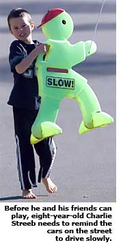 young boy puttng out slow down sign